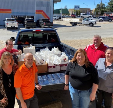 group photo of simmons associates in front of truck bed full of food care packages