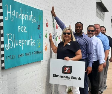 simmons bank associates posing for group photo with handprints for blueprints sign