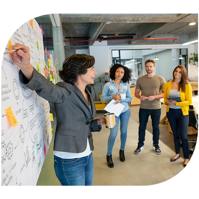 A woman pointing at a white board while leading a business team meeting