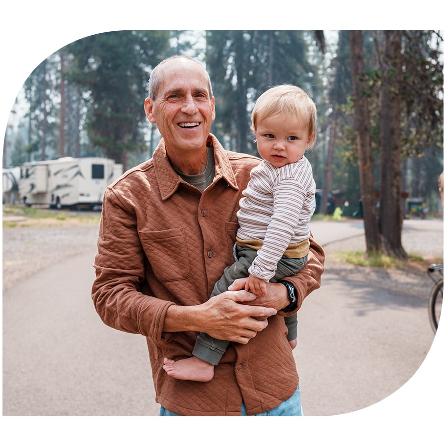 A man holding his grandchild at a community camping ground