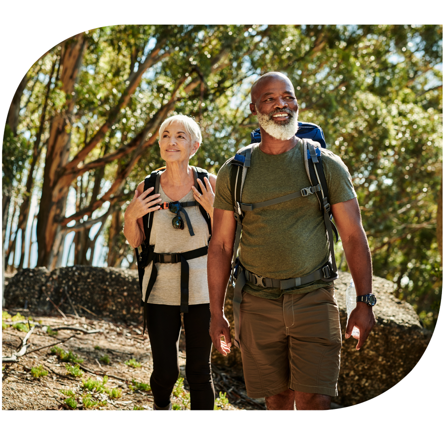 middle aged man and woman smiling while hiking with backpacks