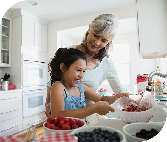 woman and young girl washing fruit in kitchen