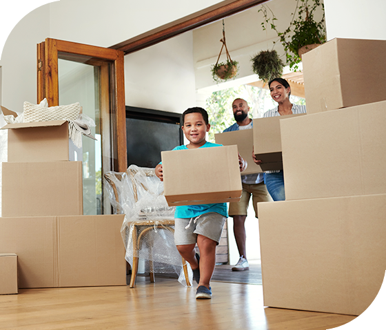 young family carrying moving boxes into new house