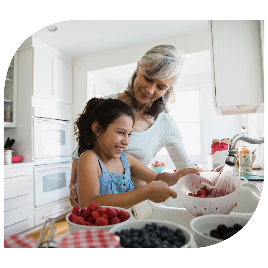 woman and young girl washing fruit in kitchen