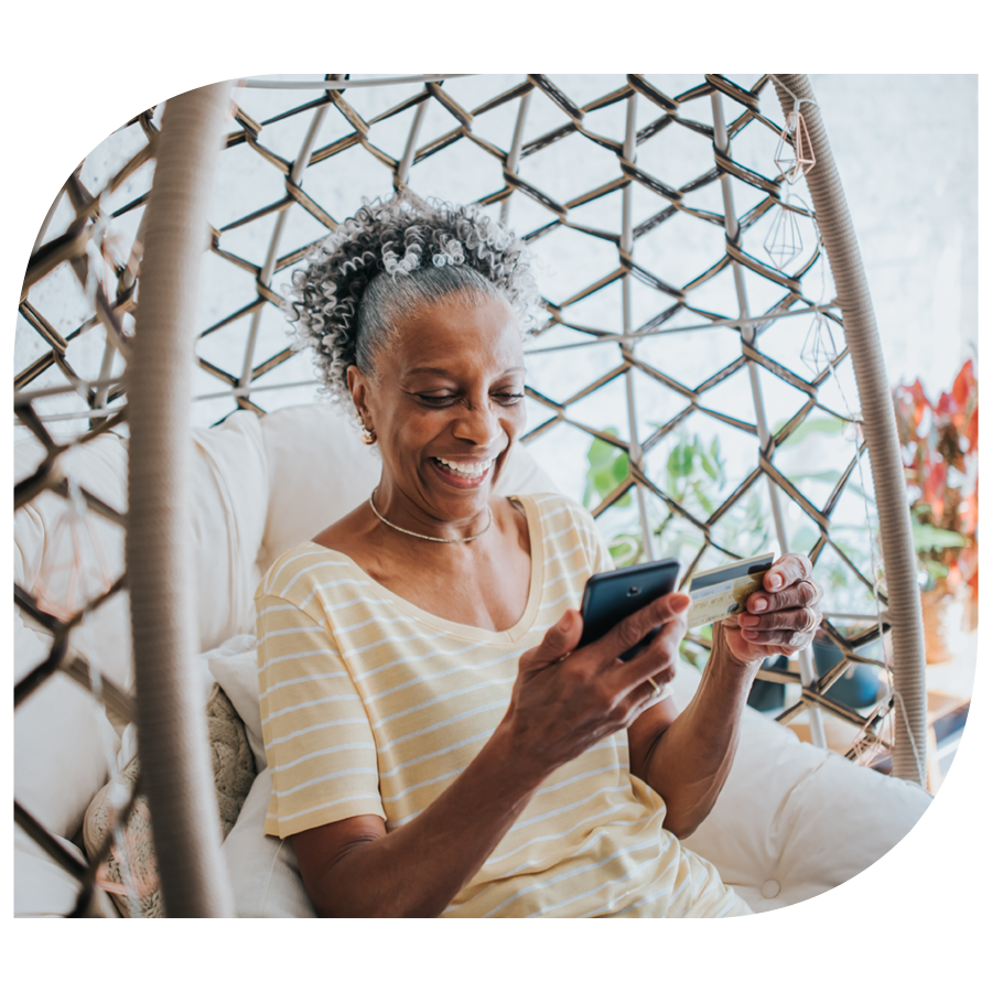 woman laughing while entering credit card info into smart phone