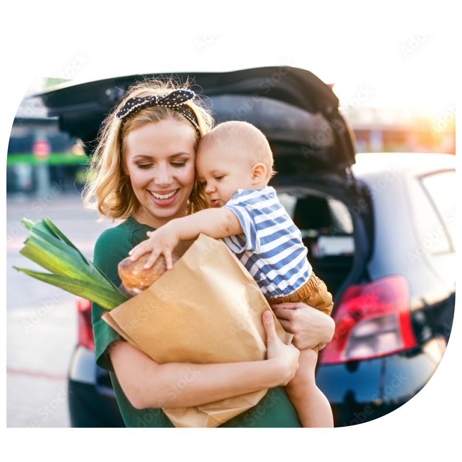 mom holding toddler and paper grocery bag