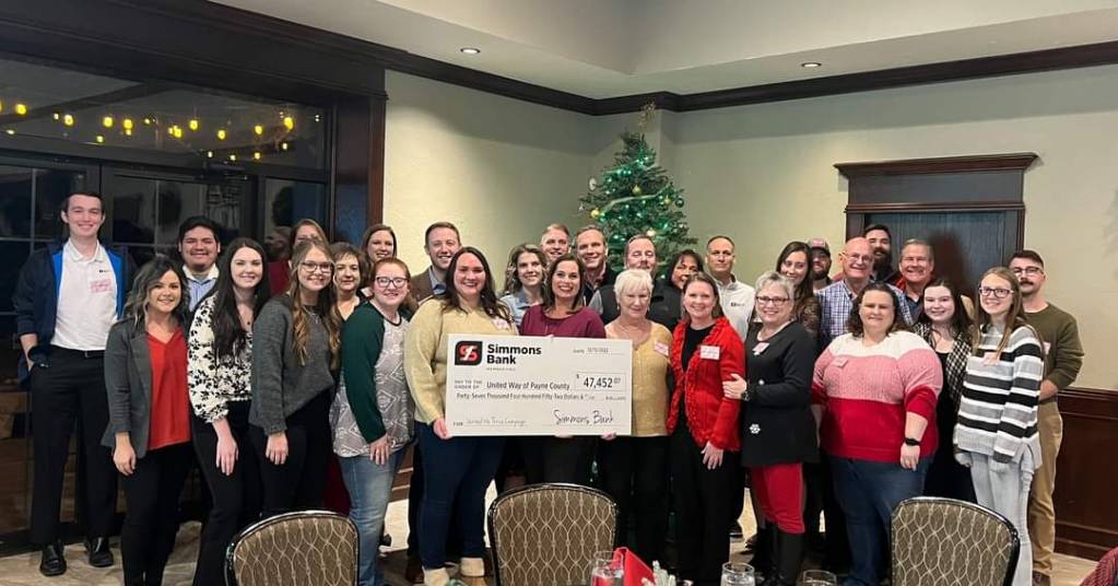 a large group of simmons associates donating a check to United Way of Payne county