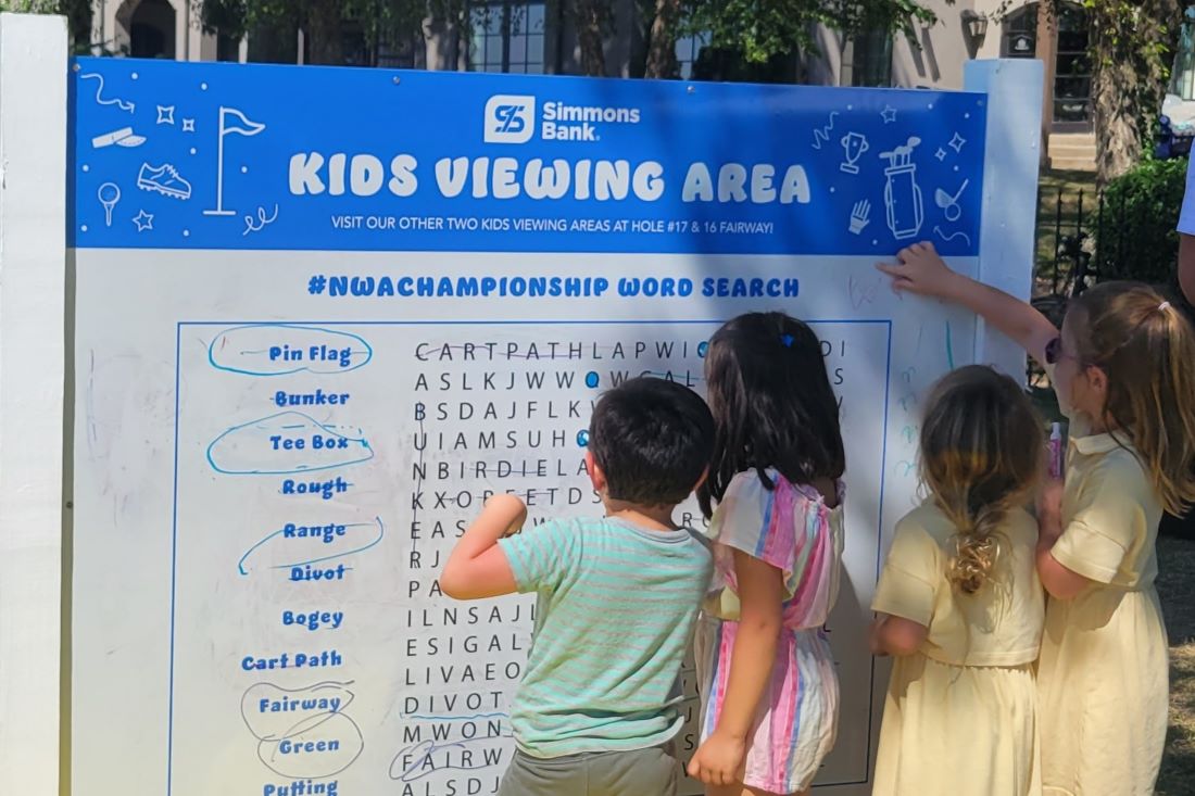 Four children working together outside on a large word search puzzle